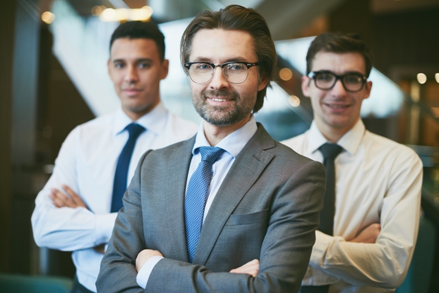 Successful boss looking at camera on background of male employees