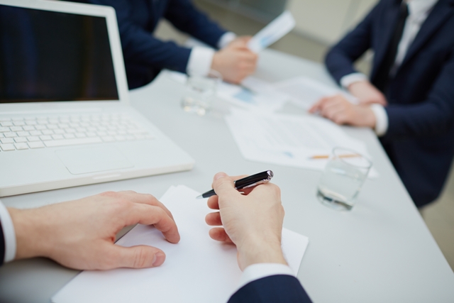 Image of human hands with pen writing business plan