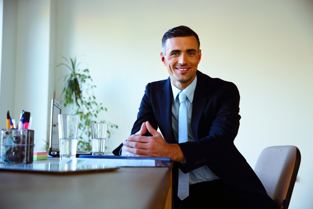 Happy businessman sitting at the table in office