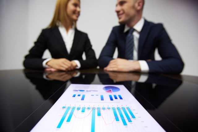 Image of business paper at workplace and business partners on background