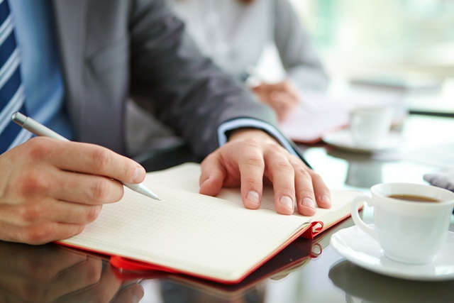 Male hand with pen over empty notebook page during planning work