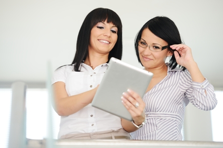 Two businesswomen working on tablet gadget with copy space