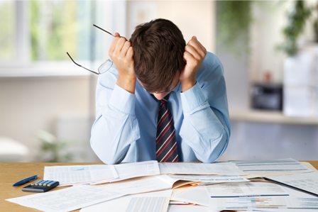 Tired young businessman holding glasses - looking down at papers
