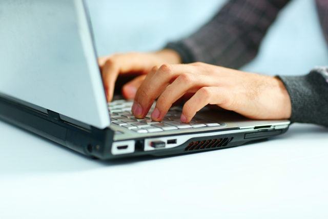 Closeup image of a male hands typing on laptop keyboard