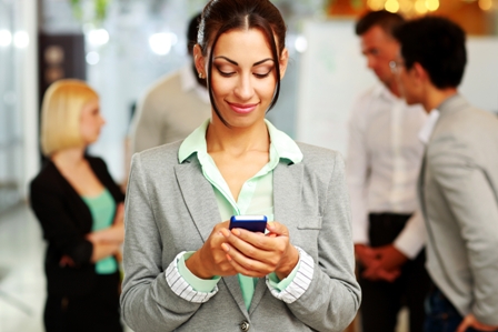 Portrait of a happy businesswoman using smartphone in front of colleagues