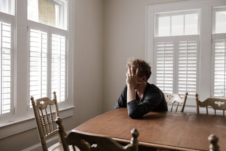 Man at table holding his head