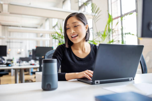 Asian businesswoman talking to virtual assistant at her desk. 